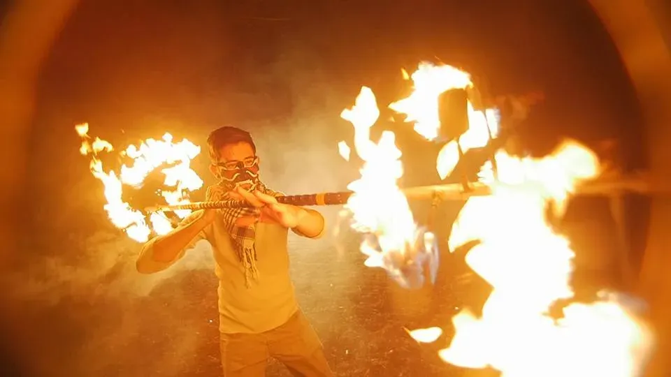 Spinning a lit fire dragon staff, flames trailing in a wide arc