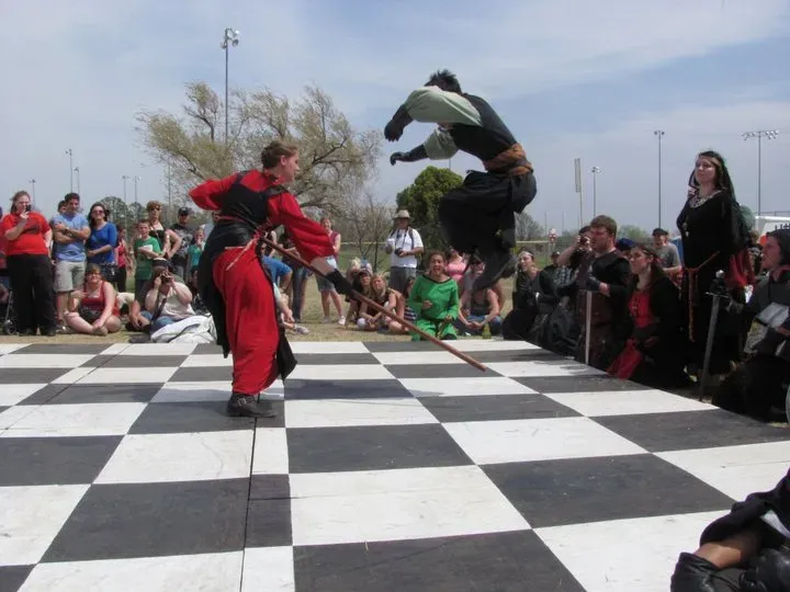 Two costumed fighters clashing with sword and shield