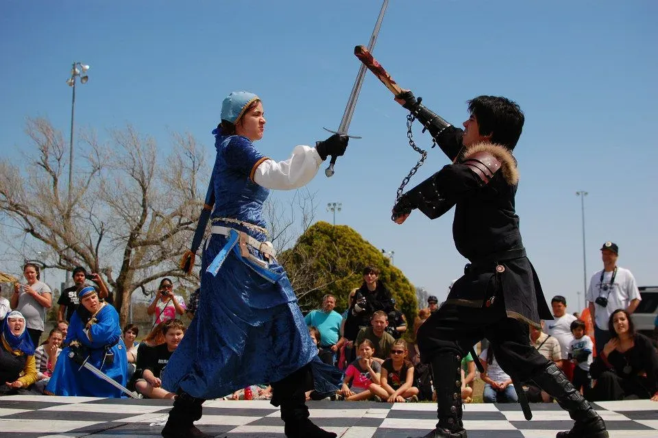 A staged rapier duel between two performers on a checkered stage