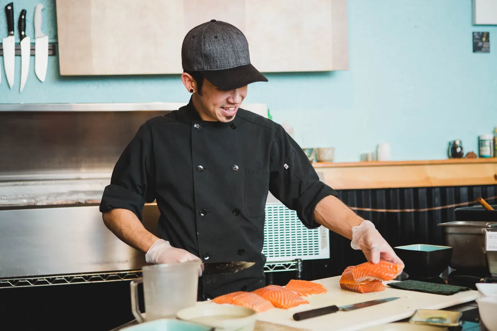 Bryan Sekine slicing a side of salmon behind a sushi bar