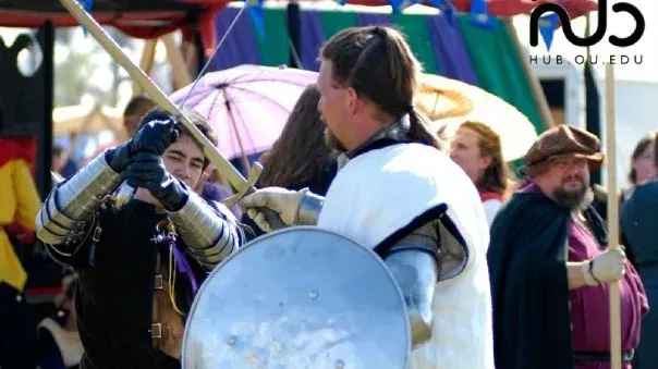 A choreographed sword and shield exchange at an outdoor festival